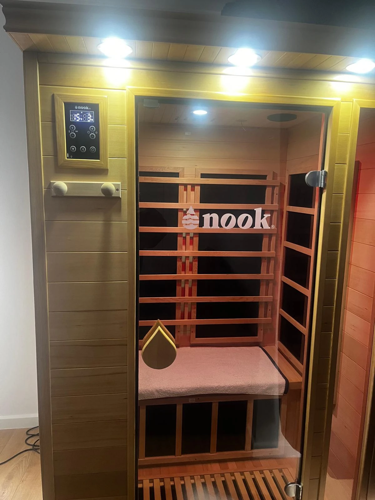 Nook-branded wooden sauna with a glass door and bench